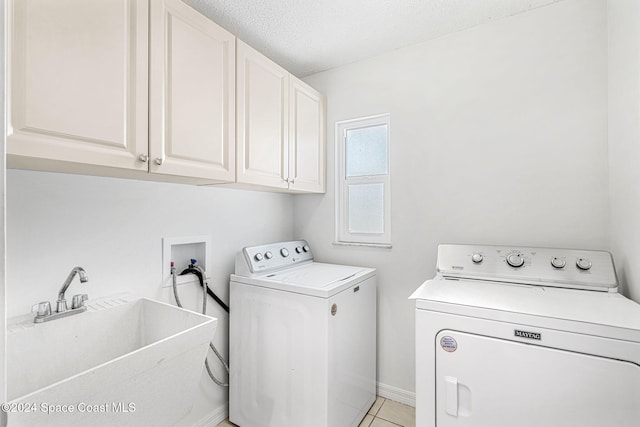 laundry area with cabinets, sink, separate washer and dryer, a textured ceiling, and light tile patterned floors