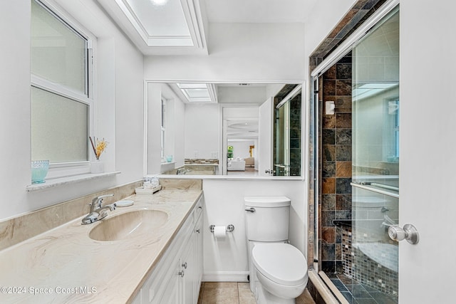 bathroom with a skylight, tile patterned floors, an enclosed shower, toilet, and vanity