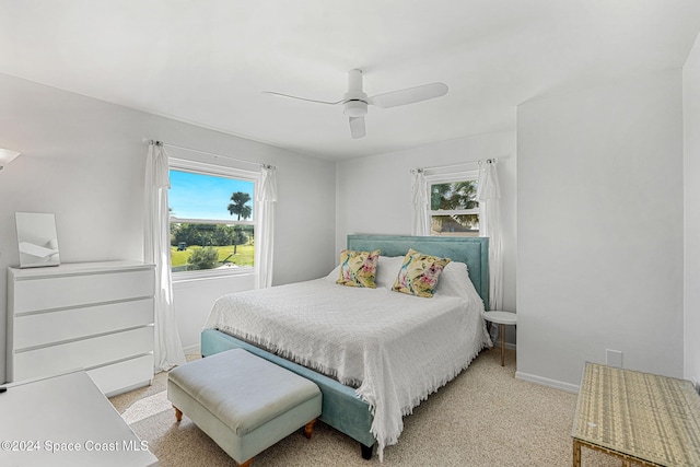 bedroom featuring ceiling fan, light colored carpet, and multiple windows