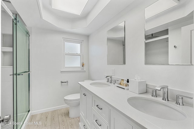 bathroom featuring vanity, a tray ceiling, hardwood / wood-style floors, toilet, and a shower with shower door