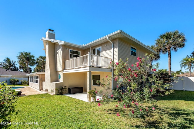 rear view of property with a lawn, a patio area, and a balcony