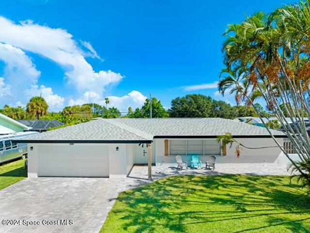 ranch-style home with a garage, decorative driveway, roof with shingles, and a front lawn