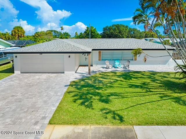 ranch-style home featuring a front lawn, decorative driveway, a garage, and stucco siding