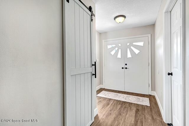 entryway featuring dark hardwood / wood-style floors, a barn door, and a textured ceiling