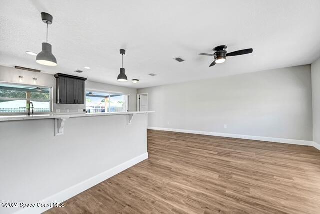 kitchen featuring a breakfast bar, kitchen peninsula, hanging light fixtures, and dark wood-type flooring