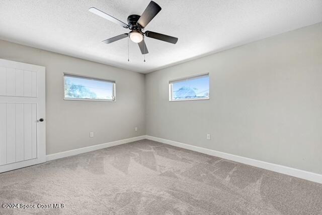 carpeted spare room with ceiling fan and a textured ceiling