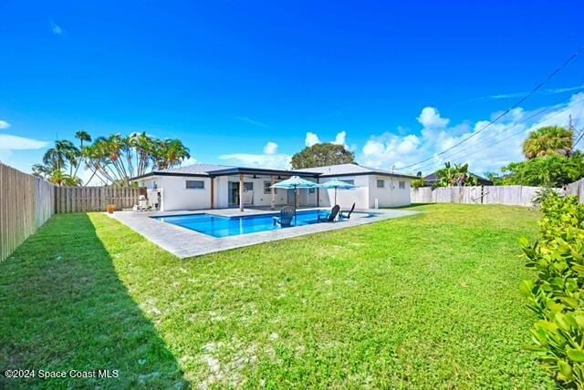 rear view of property featuring a fenced in pool and a yard