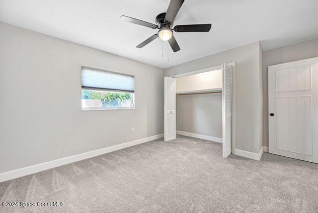 unfurnished bedroom with ceiling fan, a closet, and light carpet