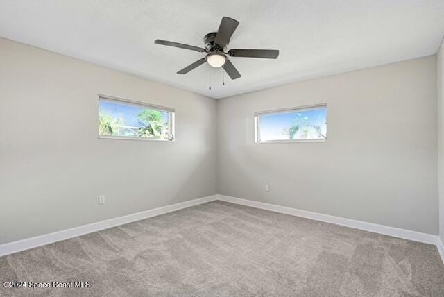 carpeted spare room featuring ceiling fan