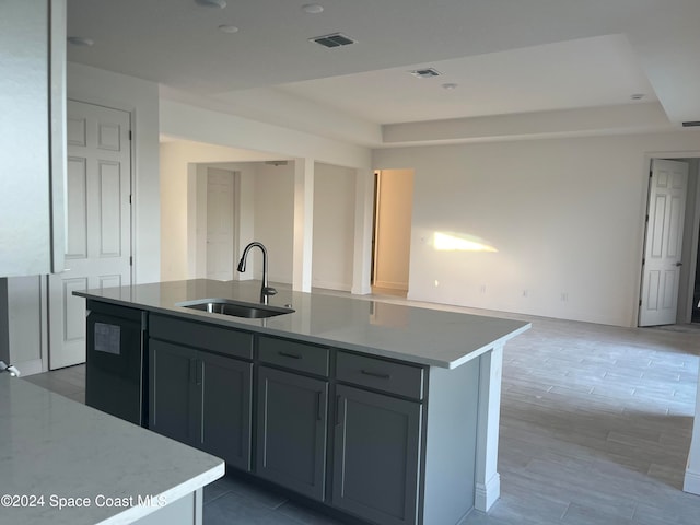 kitchen with gray cabinetry, a kitchen island with sink, sink, wood-type flooring, and black dishwasher