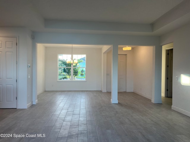 unfurnished dining area with wood-type flooring and an inviting chandelier