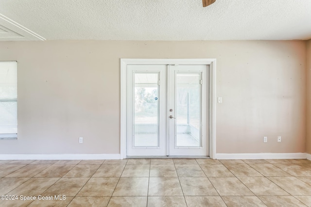 spare room featuring ceiling fan, light tile patterned flooring, a textured ceiling, and french doors