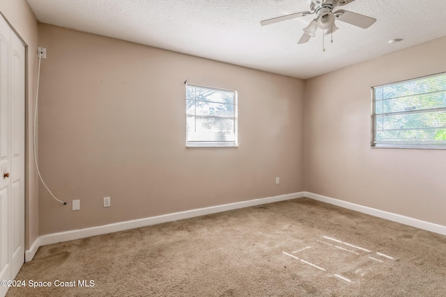 unfurnished room with ceiling fan, carpet floors, and a textured ceiling