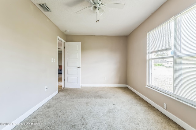 empty room featuring light colored carpet, ceiling fan, and a healthy amount of sunlight