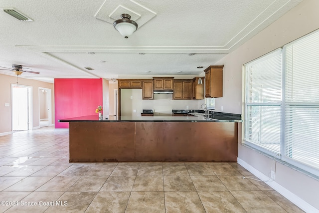 kitchen featuring kitchen peninsula, ceiling fan, light tile patterned flooring, and a textured ceiling