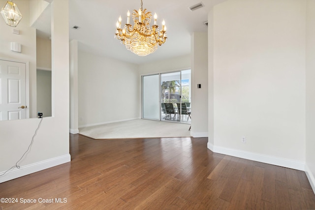 spare room with a notable chandelier and wood-type flooring