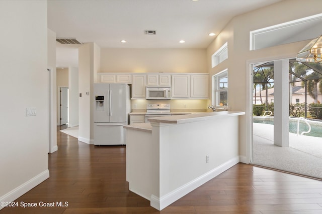 kitchen featuring dark hardwood / wood-style floors, white cabinetry, white appliances, and kitchen peninsula