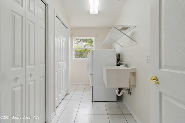 clothes washing area featuring washer / dryer, light tile patterned floors, and sink