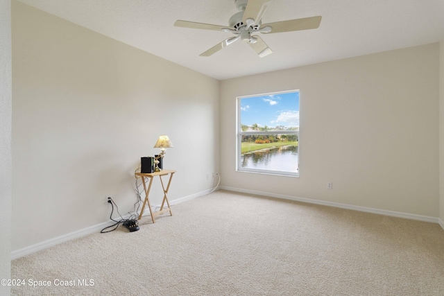 empty room with carpet flooring, ceiling fan, and a water view