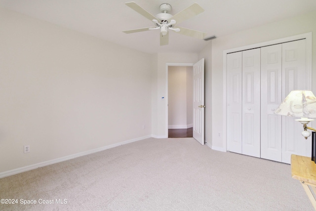 unfurnished bedroom featuring ceiling fan, light colored carpet, and a closet