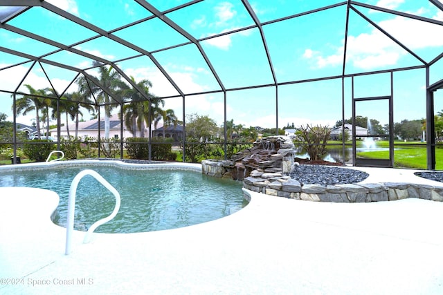 view of swimming pool with glass enclosure, pool water feature, and a water view