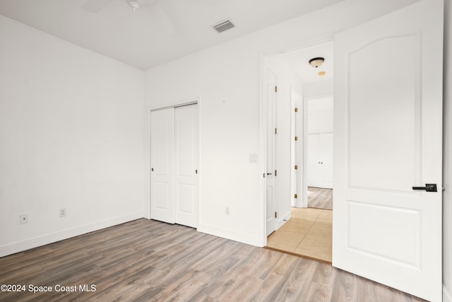 unfurnished bedroom with wood-type flooring, a closet, and ceiling fan