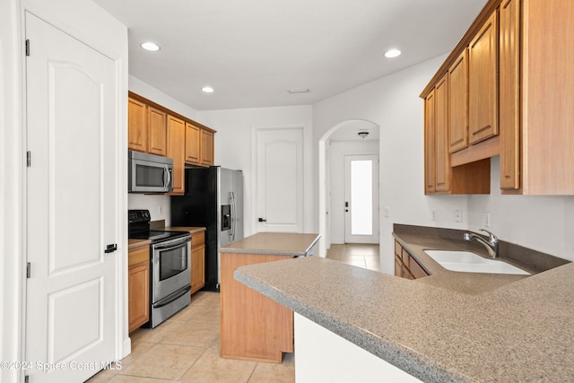 kitchen with kitchen peninsula, sink, light tile patterned floors, and stainless steel appliances