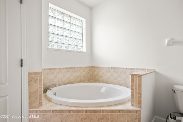 bathroom with a relaxing tiled tub and toilet