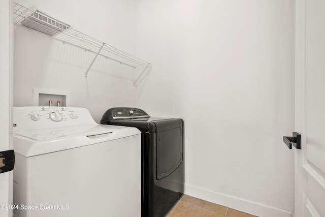 clothes washing area featuring light tile patterned floors and washer and dryer