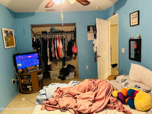 tiled bedroom featuring ceiling fan and a closet