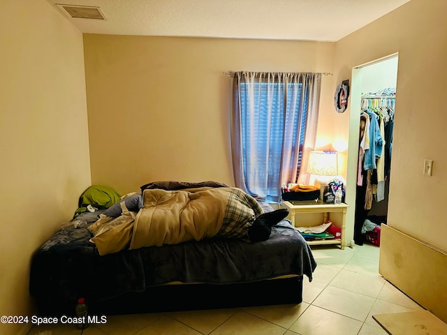 tiled bedroom with a walk in closet and a closet