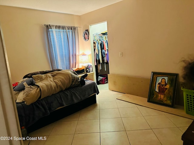 bedroom featuring a walk in closet, light tile patterned floors, and a closet