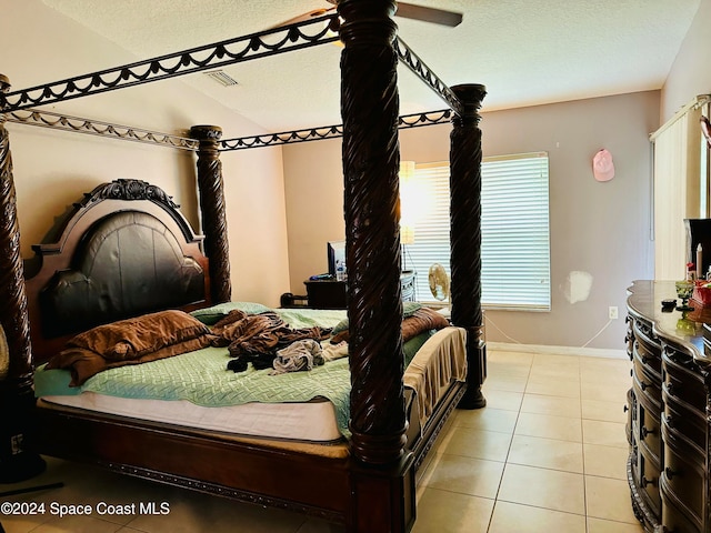 tiled bedroom with ceiling fan and a textured ceiling