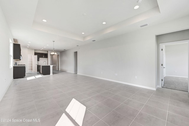 unfurnished living room featuring light tile patterned flooring and a raised ceiling