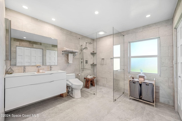 bathroom featuring tiled shower, vanity, toilet, and tile walls