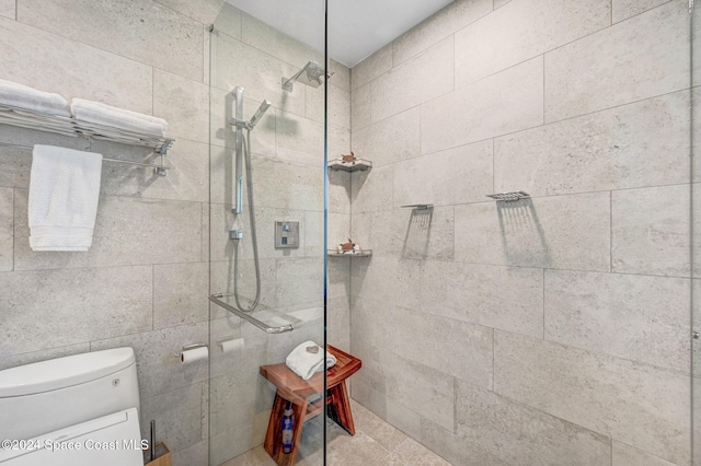 bathroom with a tile shower and toilet