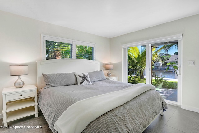 bedroom with multiple windows, a water view, and access to exterior