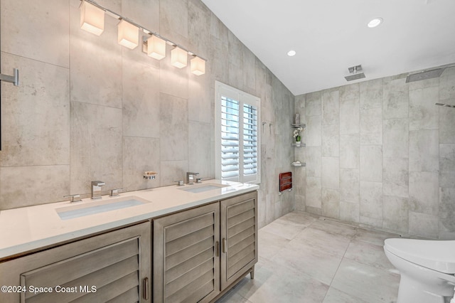 bathroom with vanity, lofted ceiling, tile patterned floors, toilet, and tile walls