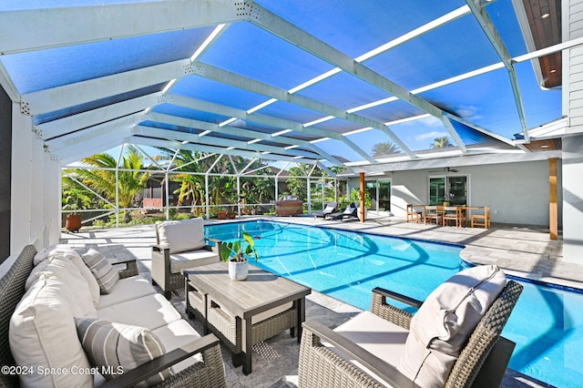 view of swimming pool featuring outdoor lounge area, ceiling fan, a patio area, and a lanai