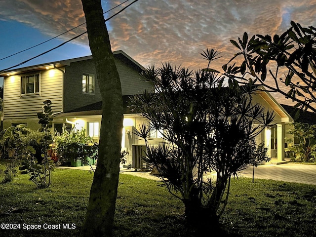 property exterior at dusk featuring a lawn