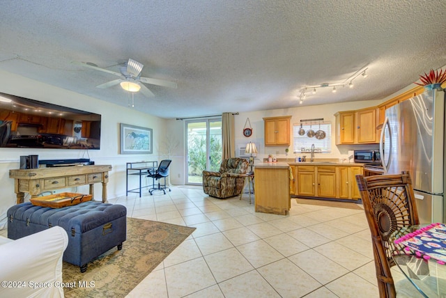 kitchen featuring sink, ceiling fan, light tile patterned floors, a textured ceiling, and appliances with stainless steel finishes