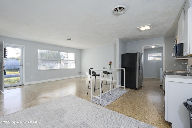 kitchen featuring white cabinets, appliances with stainless steel finishes, a kitchen bar, and a textured ceiling