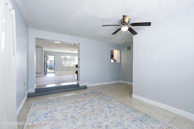 tiled empty room with ceiling fan and a textured ceiling