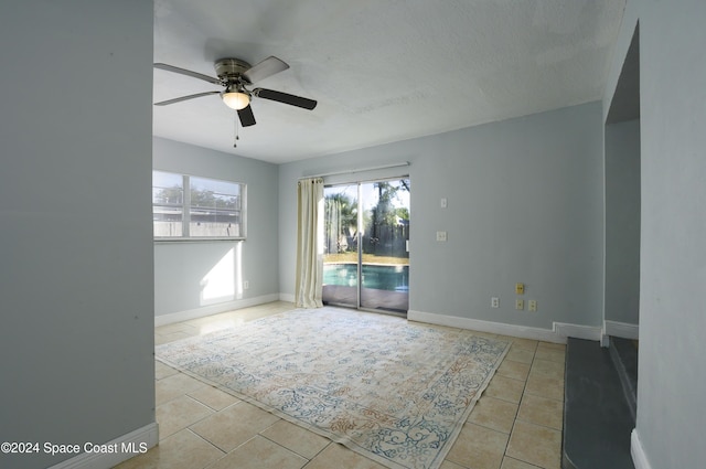 spare room with ceiling fan, light tile patterned floors, and a textured ceiling