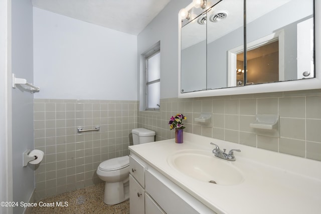 bathroom featuring vanity, tile walls, and toilet