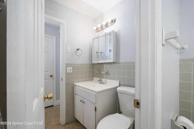 bathroom with vanity, toilet, and tile walls