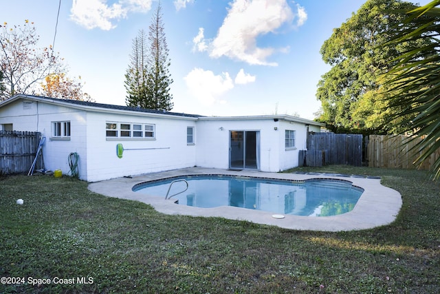 rear view of property featuring a lawn and a fenced in pool