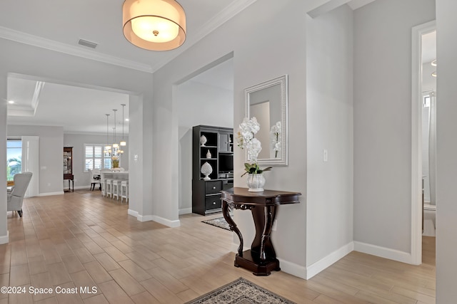 entryway with crown molding, light hardwood / wood-style floors, and a notable chandelier