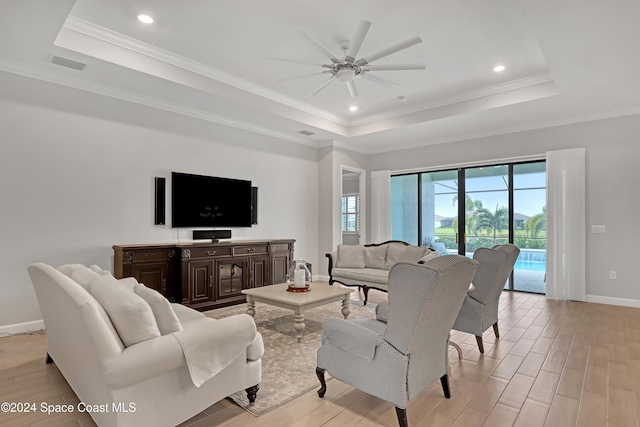 living room featuring ceiling fan, crown molding, a tray ceiling, and light hardwood / wood-style flooring