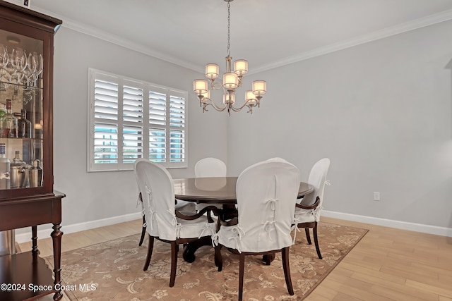 dining room with light hardwood / wood-style floors, ornamental molding, and an inviting chandelier